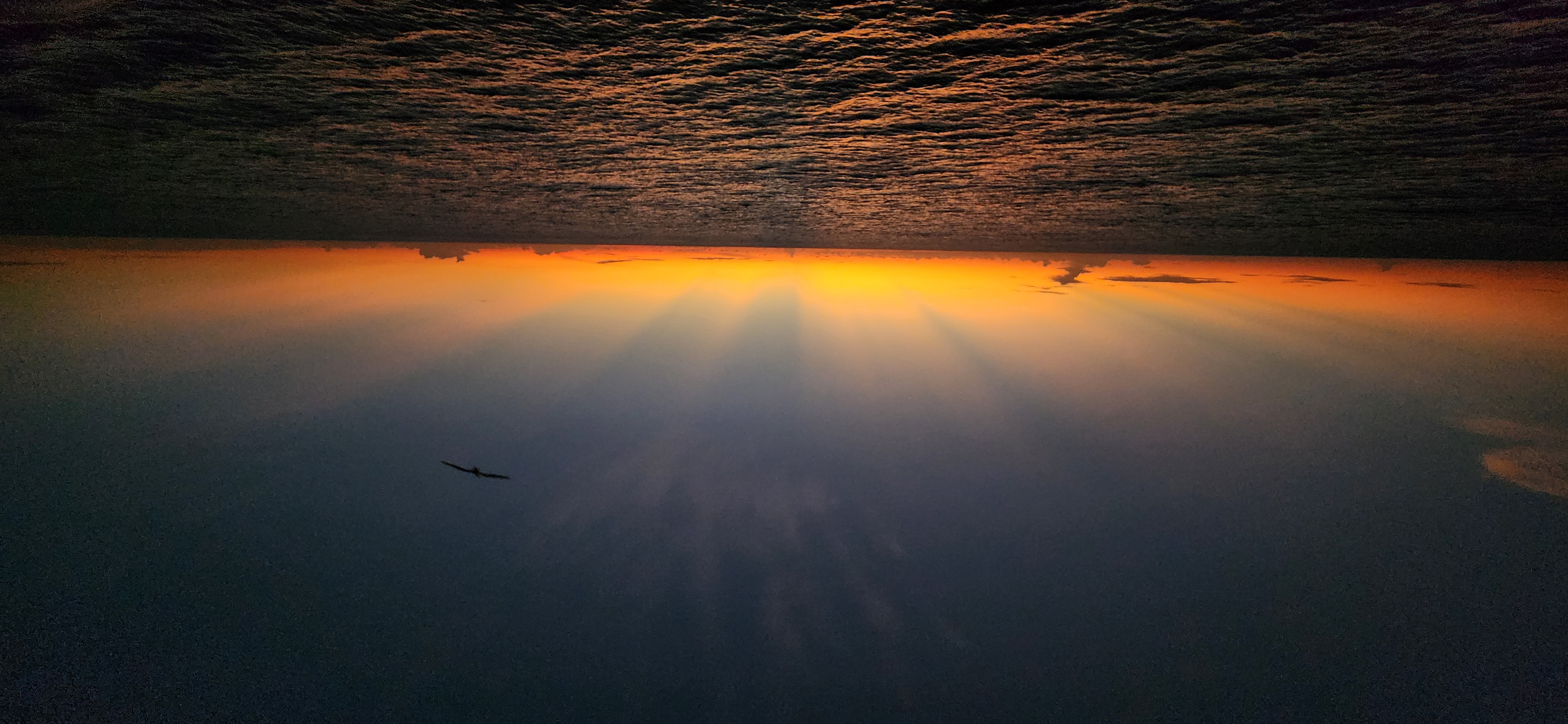 Clouds blocking sunlight over the horizon show high in the atmosphere long after the sun has set.